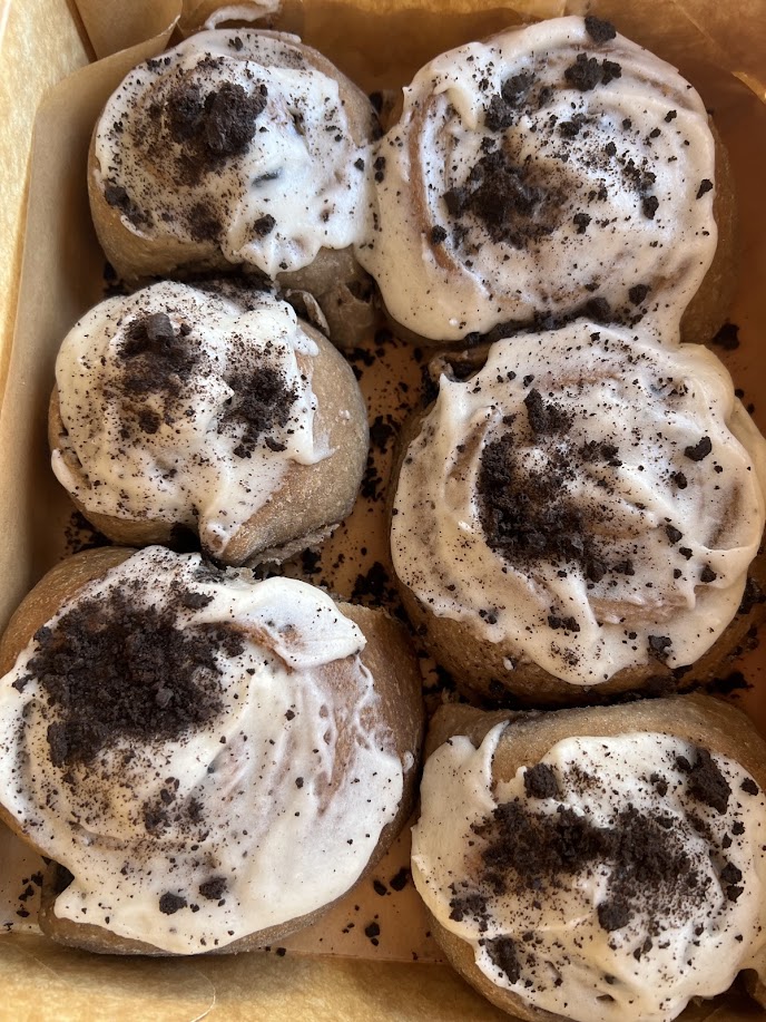 Caja con seis rolls de canela cubiertos de glaseado y galleta de chocolate triturada